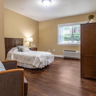 A cozy bedroom with a single bed, armchair, and wooden flooring.