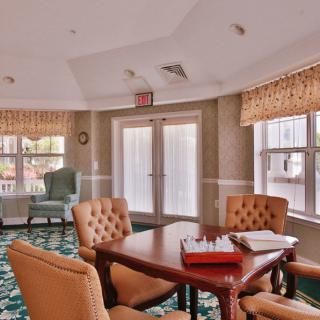 A well-lit meeting room with a table and chairs, featuring large windows and classic decor.