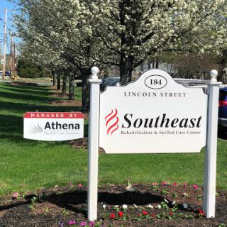 A visible sign displaying Athena and Southeast businesses located on Lincoln Street amidst blooming trees.