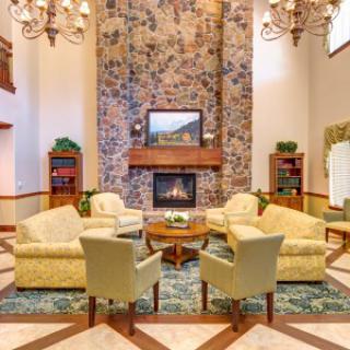 A cozy living room with a stone fireplace, elegant chandeliers, and comfortable seating arrangements.