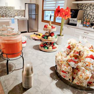 A beautifully arranged kitchen table featuring snacks, drinks, and decorative elements for a festive gathering.