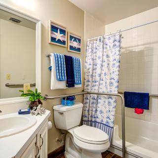 A well-organized bathroom with a shower, toilet, and sink, decorated with blue and white accents.