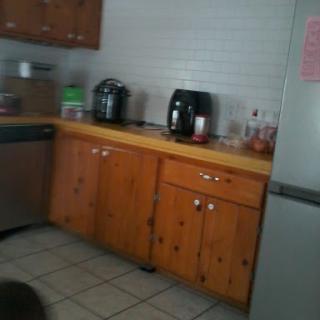 A view of a home kitchen featuring wooden cabinets and various kitchen appliances.