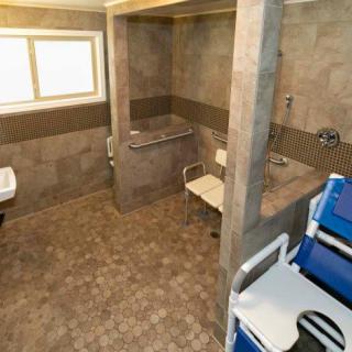 A spacious, wheelchair-accessible bathroom equipped with handrails and a shower chair.