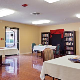 A spacious community room featuring tables and chairs, complemented by bookshelves filled with books.