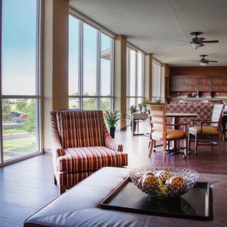 A modern living and dining space with large windows, featuring a striped chair and ample natural light.