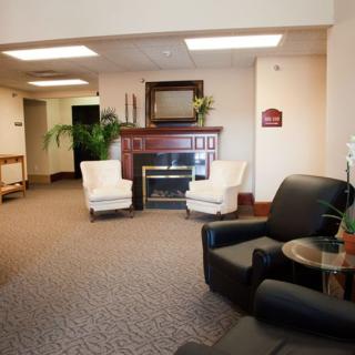 A cozy lobby with a seating area featuring armchairs and a fireplace beneath a mounted television.