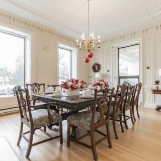 A beautifully decorated dining room with a chandelier and large windows letting in natural light.