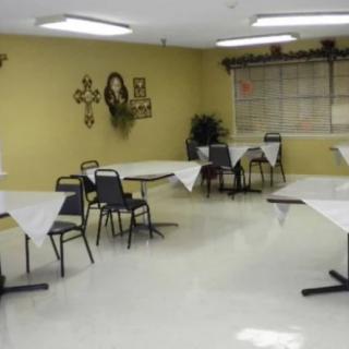 A decorated room with tables covered in white cloths and arranged with chairs.
