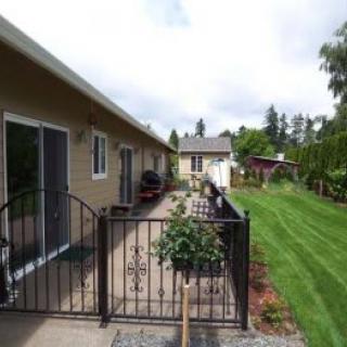 A backyard view featuring a patio with a fence, a well-maintained lawn, and surrounding greenery.