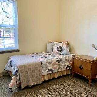 A small bedroom with a single bed, nightstand, and a window.