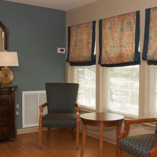 A cozy living room corner with two chairs, a small table, and window blinds.