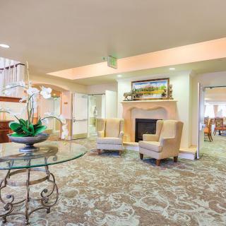 A cozy lobby with armchairs, a fireplace, and a glass table.