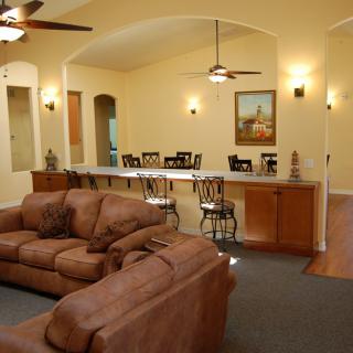 Cozy living room with sofas and a bar area, featuring archways and warm lighting.