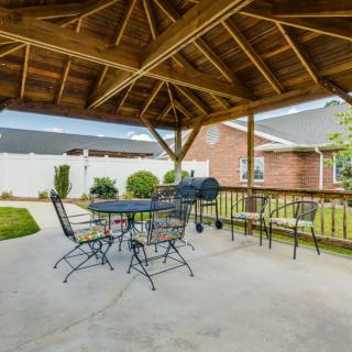 Covered patio area with a gazebo, outdoor seating, and a grill in the backyard.