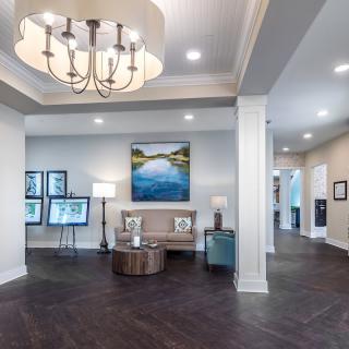 A modern lobby with stylish decor, featuring a chandelier, artwork, and a comfortable seating area.