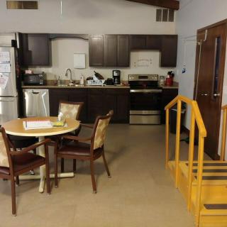 A cozy kitchen and dining area featuring a small round table, chairs, and indoor stairs near modern appliances.
