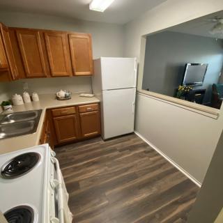 A modern apartment kitchen with wooden cabinets and a white refrigerator.