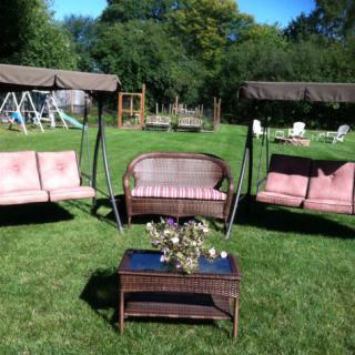 Outdoor garden seating area with swings and wicker furniture.