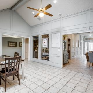 A spacious kitchen and dining area with a ceiling fan and tiled flooring.