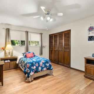 A cozy bedroom with a single bed, wooden flooring, and a ceiling fan.