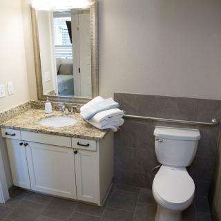 A clean and modern bathroom featuring a sink, toilet, and mirror with neatly folded towels on the counter.