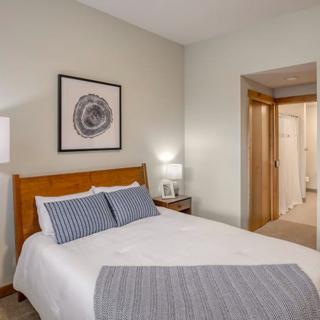 A cozy bedroom with a neatly made bed, wall art, and a bedside lamp.