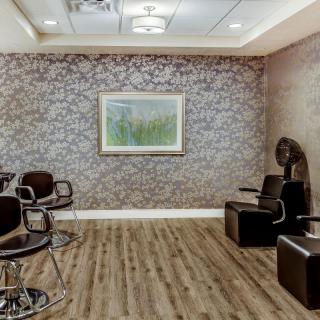 A modern salon interior with stylish chairs, a hair dryer, and floral wallpaper.