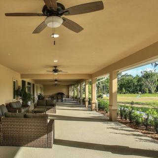 A spacious covered patio with comfortable seating and ceiling fans, overlooking a garden.