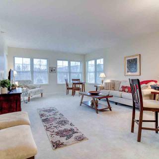 A spacious living room with comfortable seating, large windows, and modern decor.