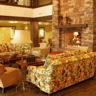 A cozy living room with a rustic fireplace and floral sofas.