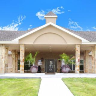 A welcoming building entrance with a well-maintained lawn and clear blue sky.