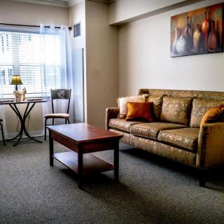 A cozy living room with a sofa, coffee table, and a small dining area by the window.
