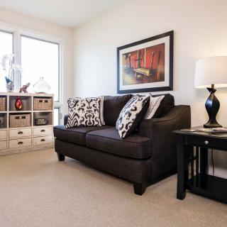 A cozy living room with a dark sofa, decorative cushions, framed artwork, and stylish storage baskets.