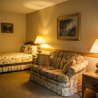 A cozy living room with a bed and sofa illuminated by warm lamps.