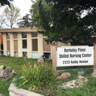 An exterior view of the Berkeley Pines Skilled Nursing Center with a visible sign and surrounding greenery.