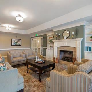 A cozy living room with comfortable seating, a central table, and a fireplace surrounded by elegant decor.