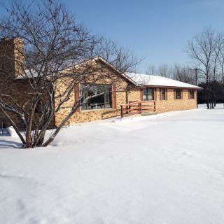 A house surrounded by snow on a sunny winter day.