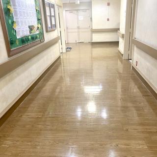 A clean and empty hospital hallway with polished floors and bright lighting.