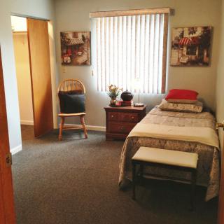 A simple and tidy bedroom with a single bed, chair, and decorative elements.
