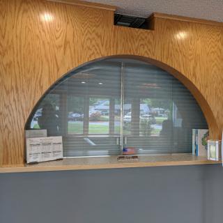A modern reception area featuring a wooden curved counter and a sliding window.
