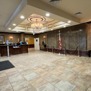 A spacious hotel lobby featuring elegant decor, a reception desk, and tiled flooring.