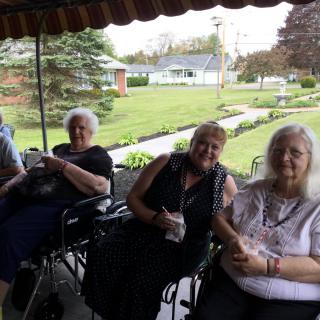 A group of elderly people sitting on a porch, enjoying the outdoors.