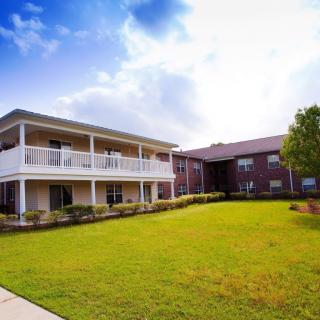 A two-story residential building with a lawn and clear sky.