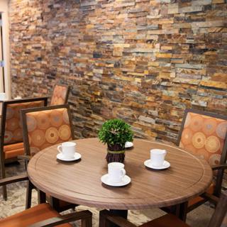 A cozy dining area with a round wooden table, surrounded by chairs and set against a stone accent wall.