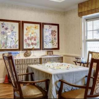 A cozy dining room with floral artwork and a table set for four.