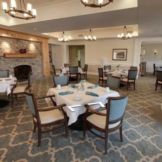 An elegant dining room with neatly arranged tables and a cozy fireplace.