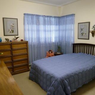 A cozy bedroom with a bed, dresser, and blue curtains.
