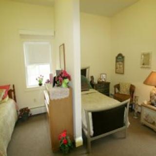 A shared bedroom with two beds separated by a partition, featuring various furniture and decor.