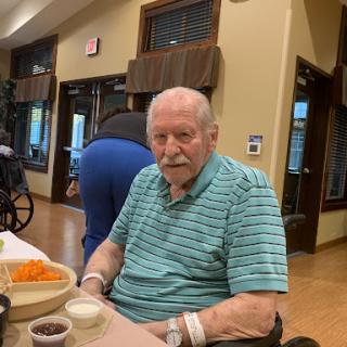An elderly man enjoying a meal in a retirement home.